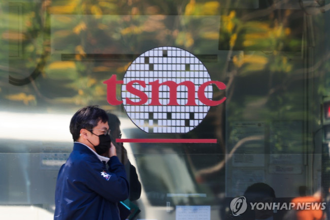 TSMC 로고 앞을 지나는 행인 