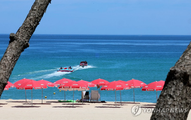 뙤약볕에 텅 빈 백사장 파라솔